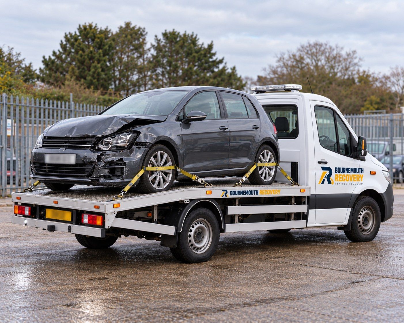 Car with front-end accident damage secured on a Bournemouth Recovery flatbed truck